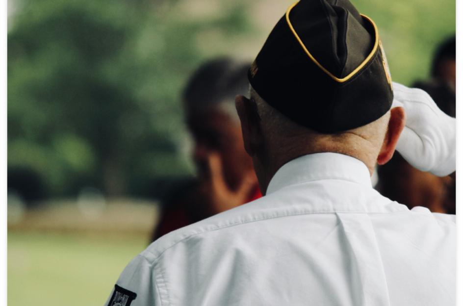 Man from back in military suit saluting other people